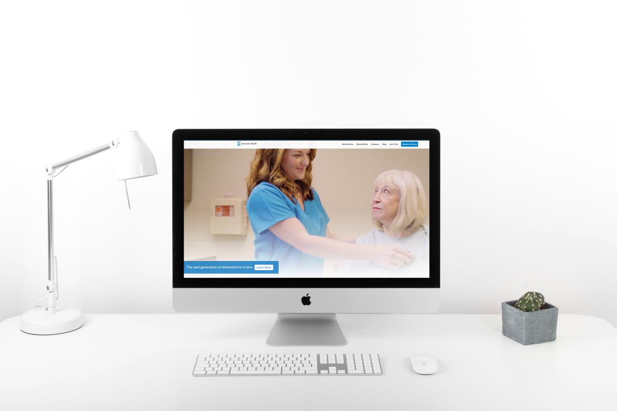 Innovator Health homepage on a iMac computer sitting on white desk with white lamp and cactus vase 
