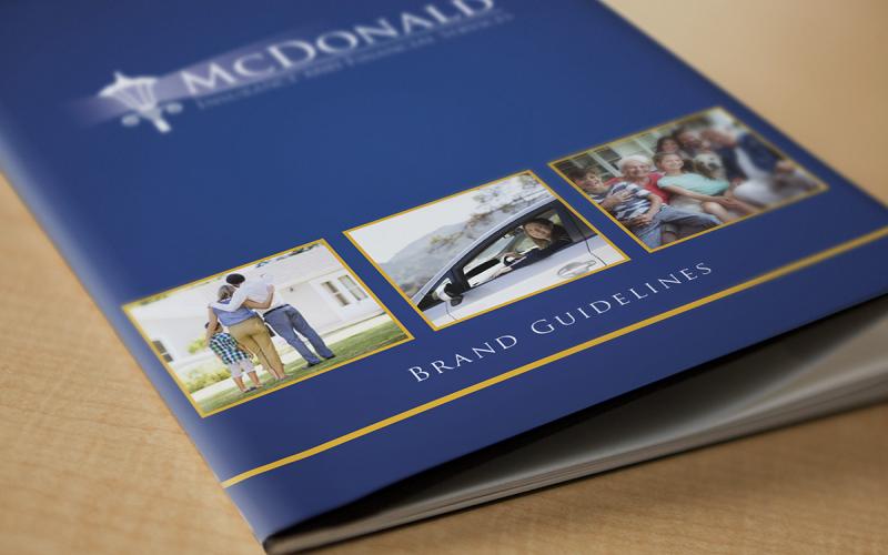 Close up of brand standards guide cover that has McDonald Insurance logo and text that reads 'brand guidelines'